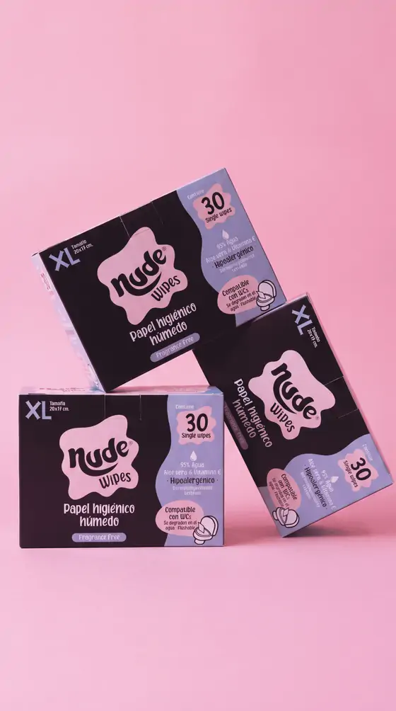 Tres cajas XL de NUDE apiladas en diagonal sobre fondo rosado.