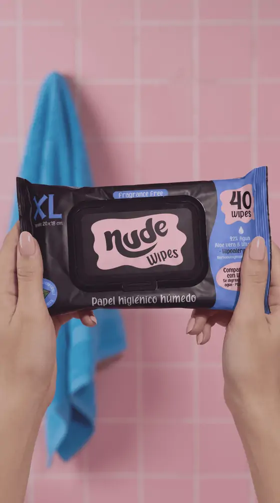Dos manos sostienen el pack de 40 unidades frente a una pared de azulejos rosados.
